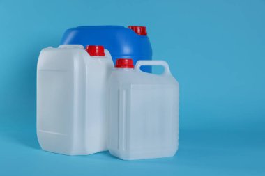 Different plastic canisters on light blue background, space for text