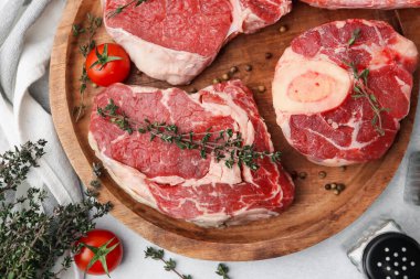 Çiğ et parçaları, baharatlar ve domatesler açık gri masada, düz yatıyordu.