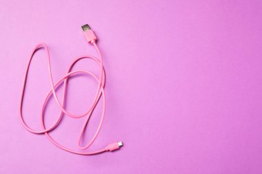 Mor arka planda pembe USB şarj kablosu, üst görüntü. Metin için boşluk