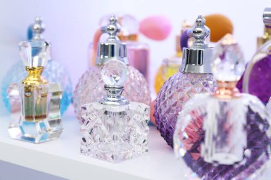 Dükkandaki raflarda farklı lüks parfüm şişeleri var.