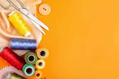 Turuncu arka planda farklı dikiş malzemeleri var. Metin için boşluk