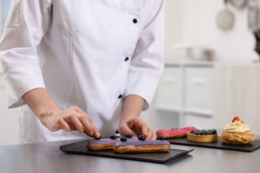 Pasta şefi mutfaktaki masada yabanmersinli pasta dekorasyonu yapıyor.