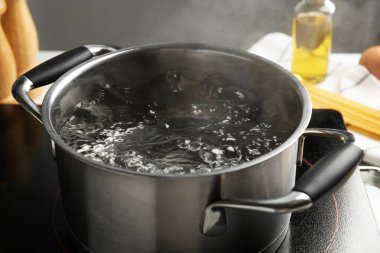 Kaynar suyla pişirme tenceresi ve beyaz masa üzerinde gri arka plan, yakın çekim