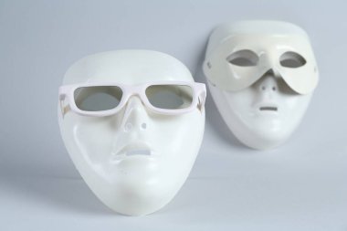 Açık gri arka planda güneş gözlüklü plastik tiyatro maskeleri