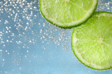 Açık mavi arka planda limon dilimli soda, yakın plan.