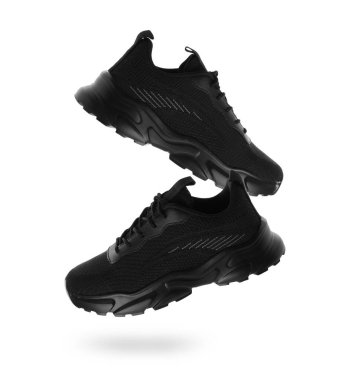 Beyaz arka planda havada şık siyah spor ayakkabılar