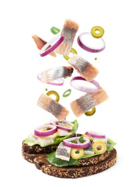 Ringa balıklı lezzetli bruschettalar ve beyaz arka planda uçan malzemeler.