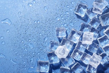 Eriyen buz ve su damlaları mavi arka planda, düz bir zeminde. Metin için boşluk