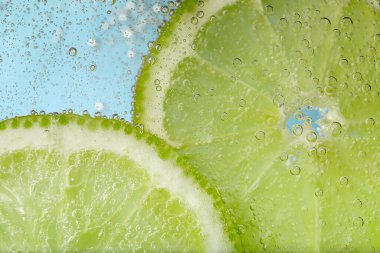 Açık mavi arka planda limon dilimli soda, yakın plan.