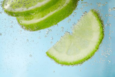 Açık mavi arka planda limon dilimli soda, yakın plan.