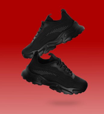 Kırmızı gradyan üzerinde havadaki şık siyah spor ayakkabılar