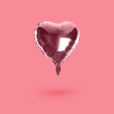 Pembe arka planda parlak kalp şeklinde bir balon.