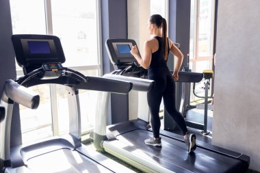 Spor salonunda koşu bandında antrenman yapan atletik kadın.