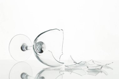 Pieces of broken wine glass on table against white background, closeup
