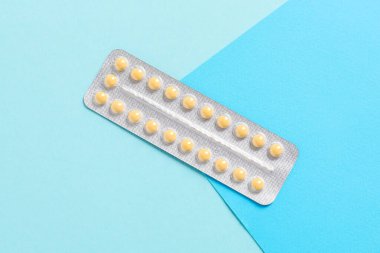 Blister of contraceptive pills on light blue background, top view