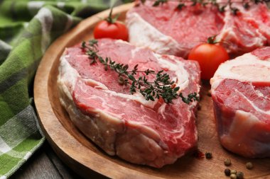 Çiğ et parçaları, domates ve baharatlar ahşap masada, yakın plan.