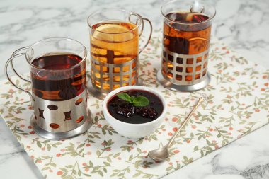 Glasses of tea in metal holders served on white marble table, closeup