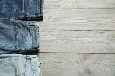 Different stylish jeans on grey wooden background, flat lay. Space for text