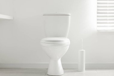 Toilet and brush on floor near white wall