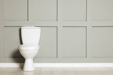 Gri duvarın yanındaki seramik klozet.