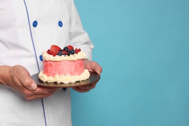 Açık mavi arka planda lezzetli pastası olan profesyonel pasta şefi, yakın plan. Metin için boşluk