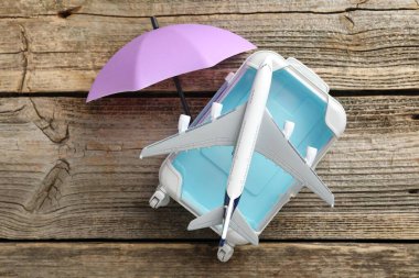 Seyahat sigortası. Uçak modeli, küçük şemsiye ve bavul ahşap masada, düz yatıyordu.