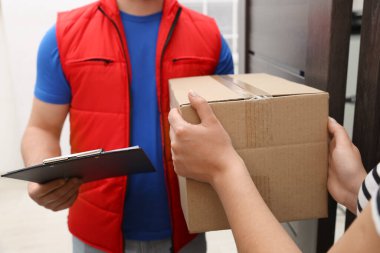 Elinde dosya olan kurye içerideki alıcıya paket veriyor, yakın plan.