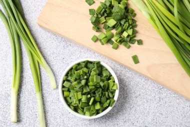 Açık gri masada taze yeşil soğanlar var. Düz.