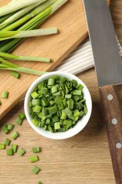 Taze yeşil soğanları kasede, bıçağı tahta masada düz bir şekilde kes.