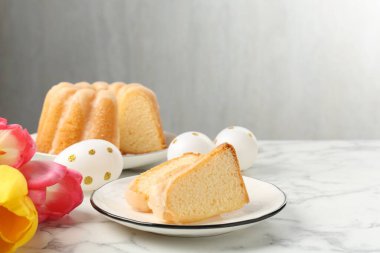 Lezzetli kek parçaları, Paskalya yumurtaları ve laleler açık mermer masada.