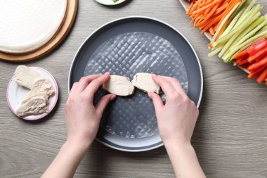 Gri ahşap masada nefis börek yapan bir kadın.