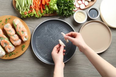 Gri ahşap masada nefis börek yapan bir kadın.