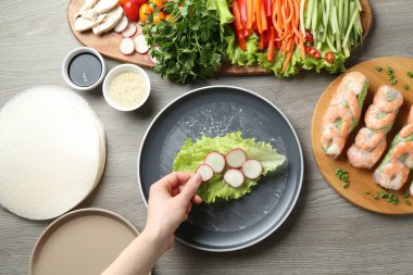Gri ahşap masada nefis börek yapan bir kadın.
