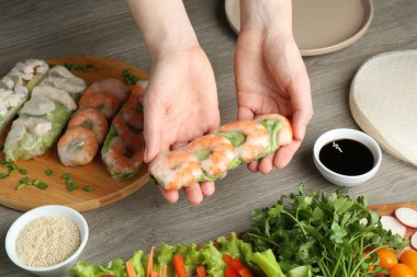 Gri ahşap masada nefis börek yapan bir kadın.