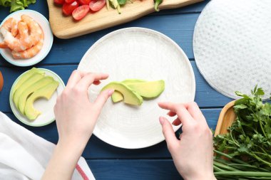 Mavi ahşap masada nefis börek yapan bir kadın.