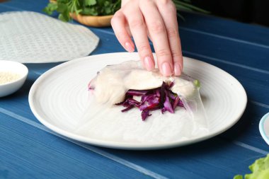 Mavi ahşap masada nefis börek yapan bir kadın, yakın plan.