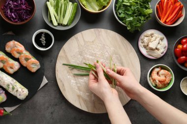 Koyu gri masada nefis börek yapan bir kadın.