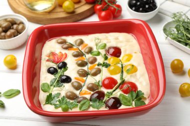 Çiğ Focaccia, sebzeli, zeytinli ve baharatlı beyaz ahşap masa, yakın plan.