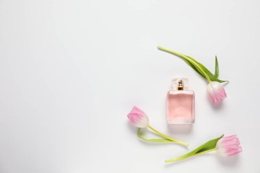 Bir şişe aromatik parfüm ve beyaz arka planda güzel laleler. Metin için boşluk