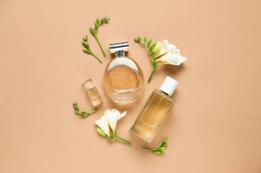 Düz kompozisyonda aromatik parfüm şişeleri ve bej arka planda güzel çiçekler vardı.