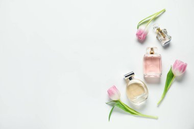 Kokulu parfüm şişeleri ve beyaz arka planda güzel çiçekler. Metin için boşluk
