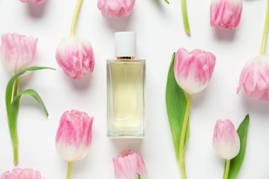 Düz kompozisyonda aromatik parfüm şişesi ve beyaz arka planda güzel laleler vardı.