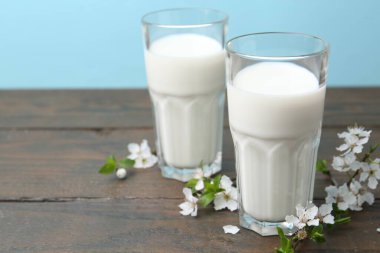 Taze süt ve çiçekler beyaz masada açık mavi arka planda