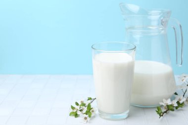 Taze süt ve çiçekler beyaz masada açık mavi arka planda. Metin için boşluk