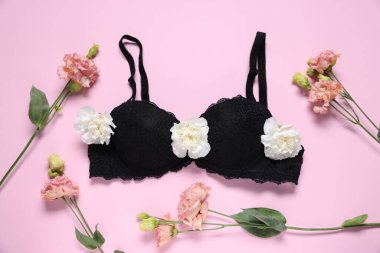 Pembe arka planda siyah sutyen ve Eustoma çiçekleri, düz yatıyordu.