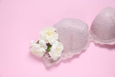 Pembe arka planda dantelli sütyen ve Eustoma çiçekleri.