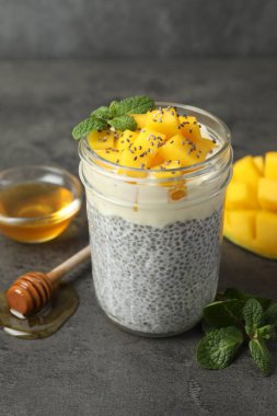 Bardakta mangolu lezzetli chia pudingi, gri desenli masada nane ve bal, yakın plan.