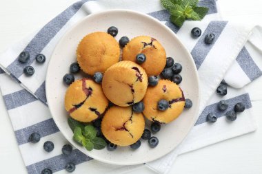 Yaban mersinli lezzetli kekler ve beyaz ahşap masada nane şekeri.