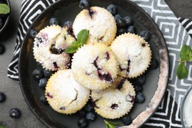 Yaban mersinli lezzetli çörekler, pudra şekeri ve siyah desenli masada nane şekeri.