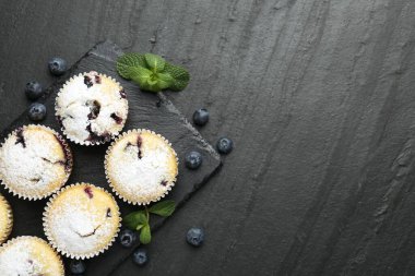 Yaban mersinli lezzetli çörekler, pudra şekeri ve siyah desenli masada nane şekeri, düz yatak. Metin için boşluk